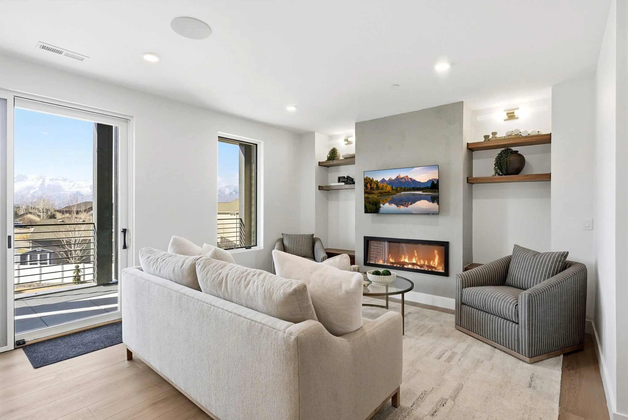 Living room with stone fireplace, mounted television, and Wasatch Range views